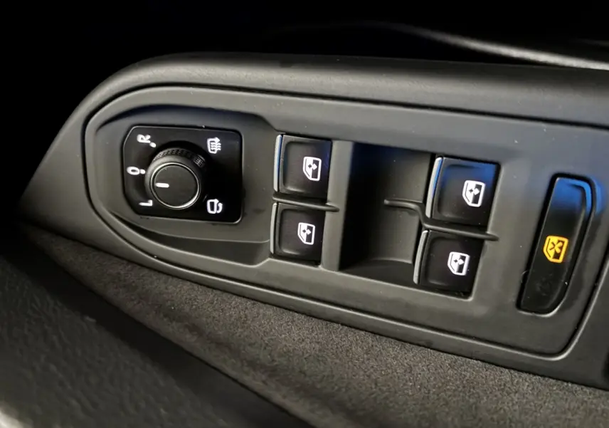 Gros plan sur les commandes des vitres et rétroviseurs côté conducteur d’une Volkswagen Golf noire 2024.