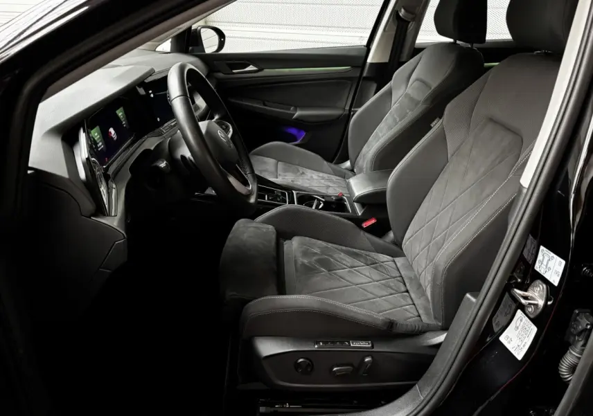 Intérieur avant droit d'une Volkswagen Golf noire 2024, sièges en tissu et alcantara avec tableau de bord digital.
