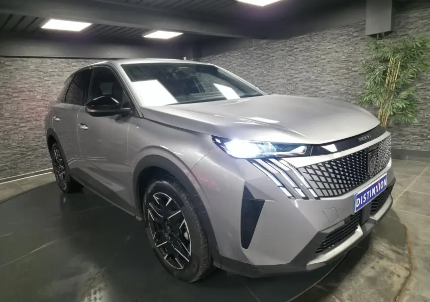 Peugeot 3008 gris métallisé vue 3/4 avant droit, avec calandre noire et feux LED distinctifs allumés.