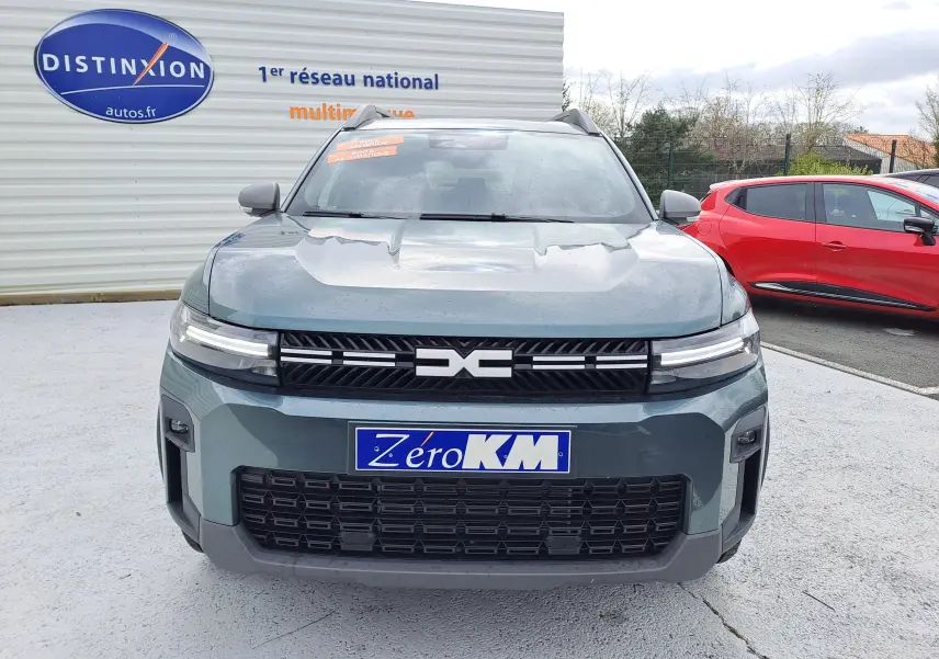 Vue de face du Dacia Bigster Hybrid 155 Journey vert cèdre avec calandre noire et plaques "Zéro KM" visibles.