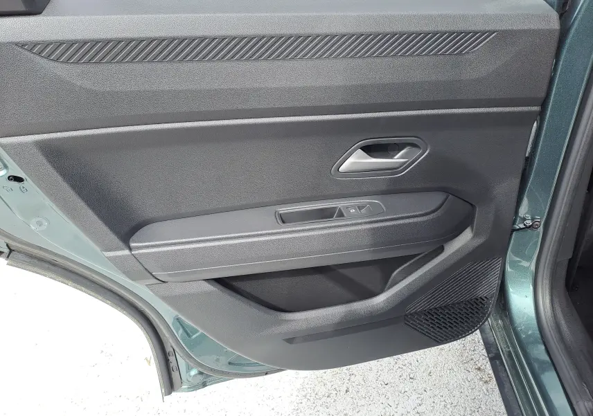 Vue rapprochée de la porte arrière gauche verte cèdre du Dacia Bigster Hybrid avec poignée et commandes de vitre intégrées.