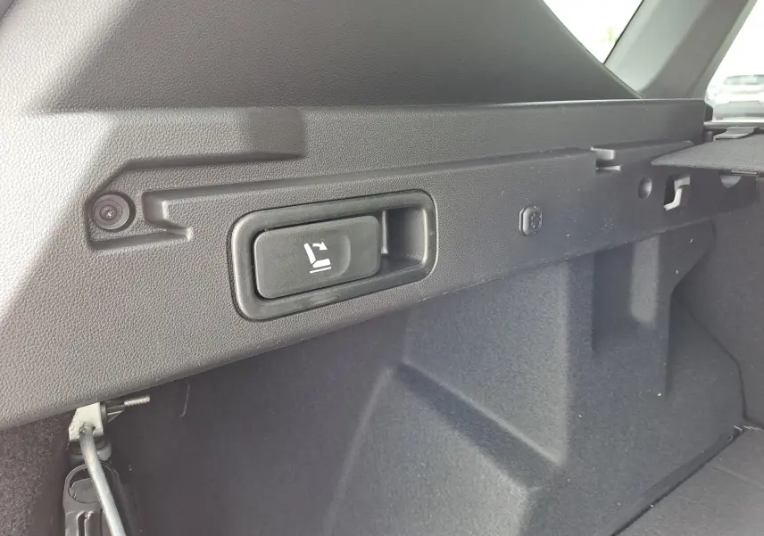 Détail du bouton de rabattement des sièges dans le coffre du Dacia Bigster Hybrid 155 Journey, intérieur noir.