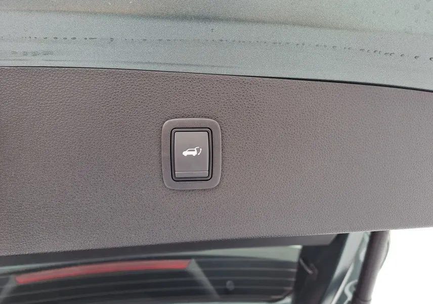 Bouton d'ouverture électrique du coffre sur la partie intérieure du hayon du Dacia Bigster vert cèdre.