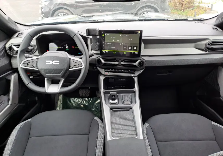 Vue intérieure avant du tableau de bord et volant du Dacia Bigster Hybrid 155 en finition Journey, avec écran tactile central.