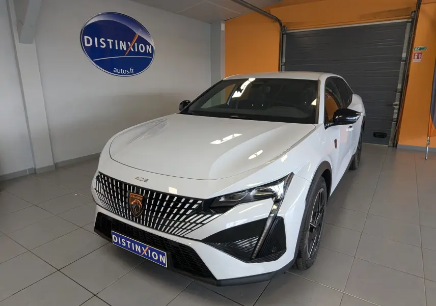 Peugeot 408 Hybrid 145 GT blanc Okenite vue 3/4 avant droit en intérieur avec calandre distinctive et jantes 19 pouces.