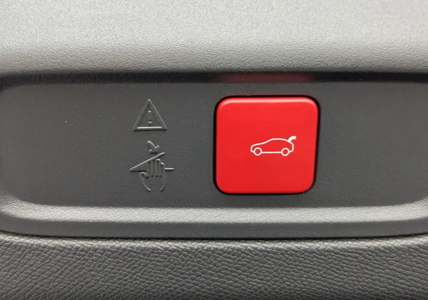 Bouton rouge de déverrouillage du coffre sur tableau de bord noir du Peugeot 408 Hybrid 145 e-DCS6 GT blanc Okenite.