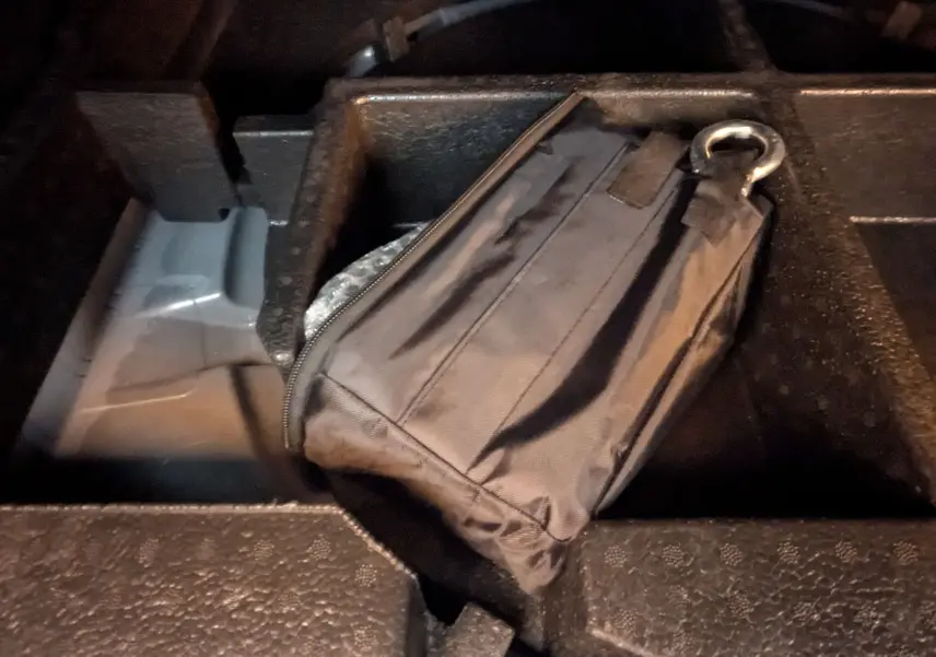 Gros plan sur une trousse noire de secours rangée dans le compartiment de rangement du coffre d'une Peugeot 408 blanche.