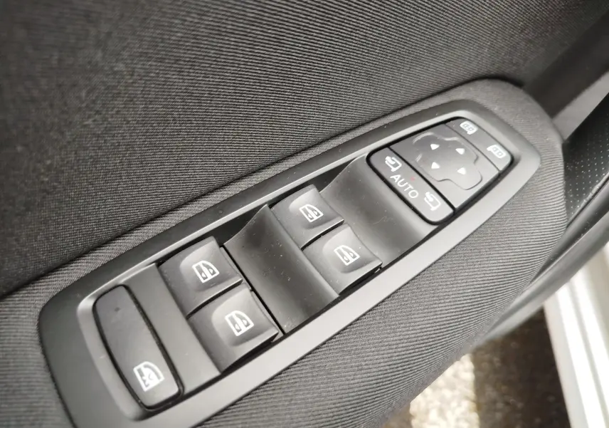Gros plan sur les commandes de lève-vitres et réglage des rétroviseurs côté conducteur de la Renault Mégane gris Titanium 2018.