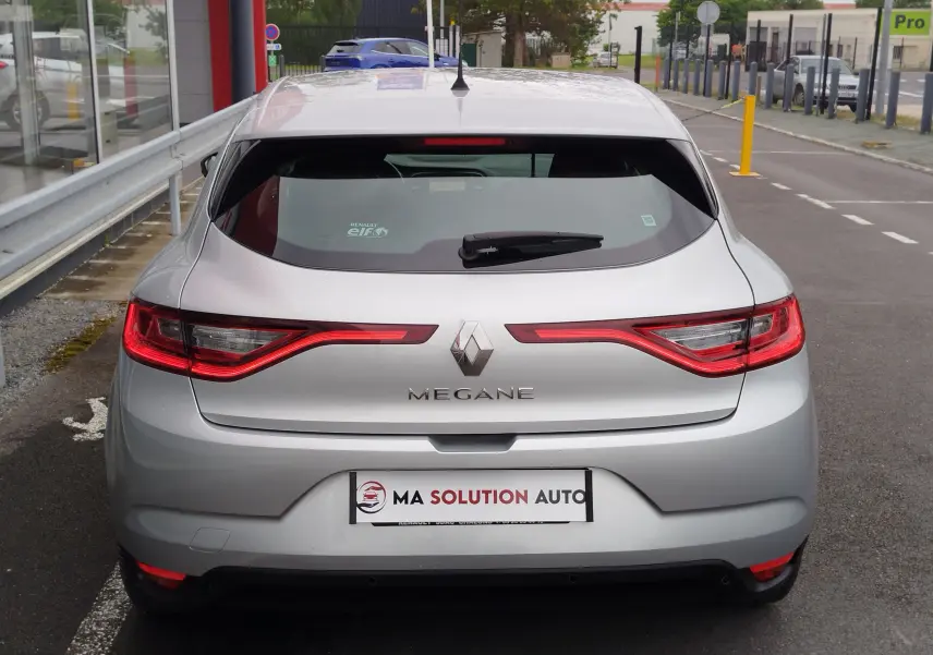 Vue arrière d'une Renault Mégane gris titanium de 2018 avec feux arrière LED allumés, garée en extérieur.
