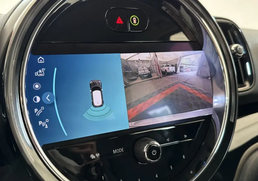 Gros plan sur l'écran tactile central rond du MINI Countryman gris clair, affichant la caméra de recul et les capteurs de stationnement.