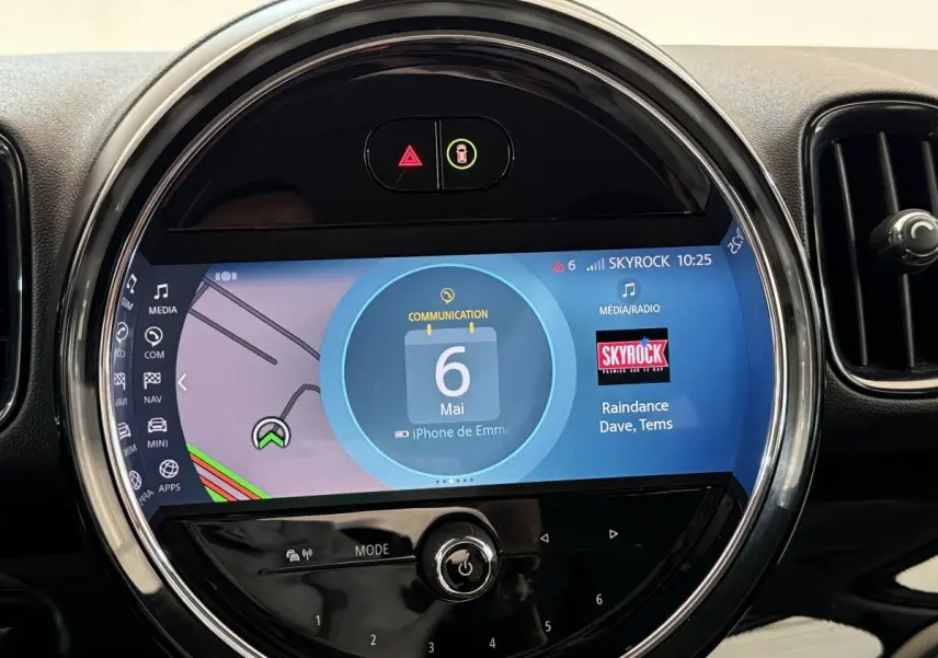 Gros plan sur l’écran tactile central rond du tableau de bord du MINI Countryman gris clair 2023, affichant la navigation et la radio.