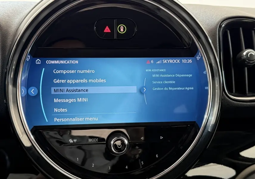 Gros plan sur l’écran tactile circulaire du tableau de bord du MINI Countryman gris clair, affichant le menu d’assistance.
