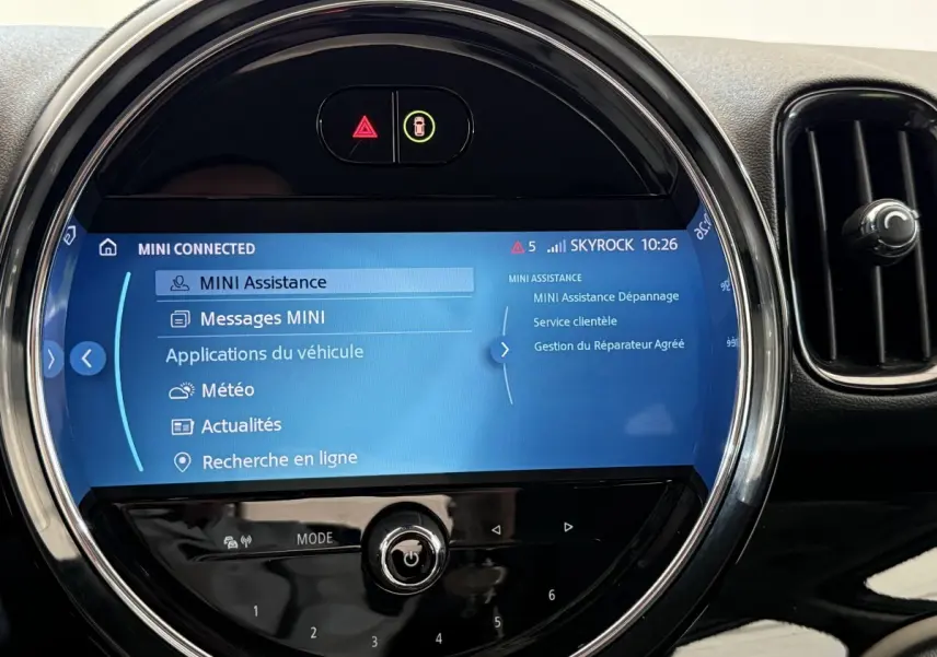 Écran tactile central rond affichant le menu MINI Connected, entouré de la console noire brillante du MINI Countryman gris clair.
