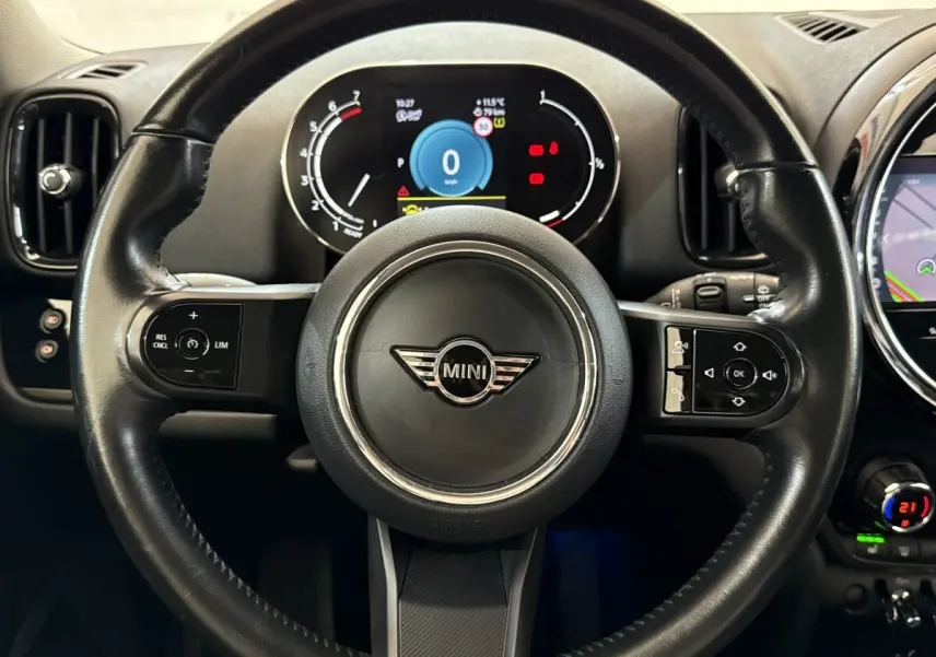 Vue rapprochée du volant cuir multifonctions noir de la MINI Countryman 2023 avec tableau de bord numérique allumé.