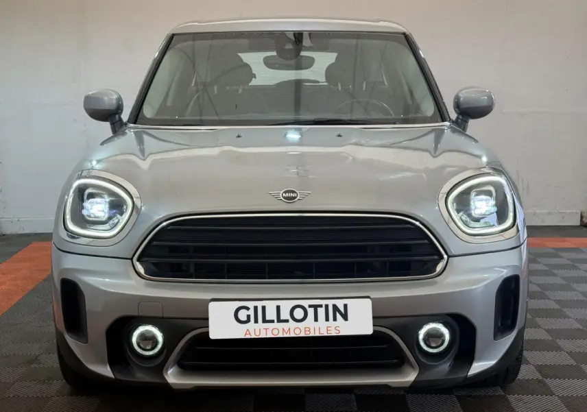 Vue avant d'une MINI Countryman gris clair avec phares et antibrouillards LED allumés en intérieur showroom.