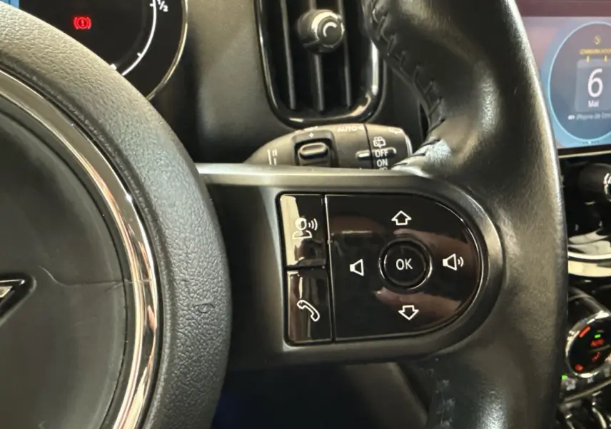 Gros plan sur le volant cuir noir multifonctions de la MINI Countryman gris clair, avec commandes intégrées visibles.