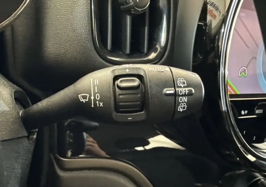 Gros plan sur la manette d’essuie-glace à gauche du volant dans l’habitacle noir d’une MINI Countryman gris clair.