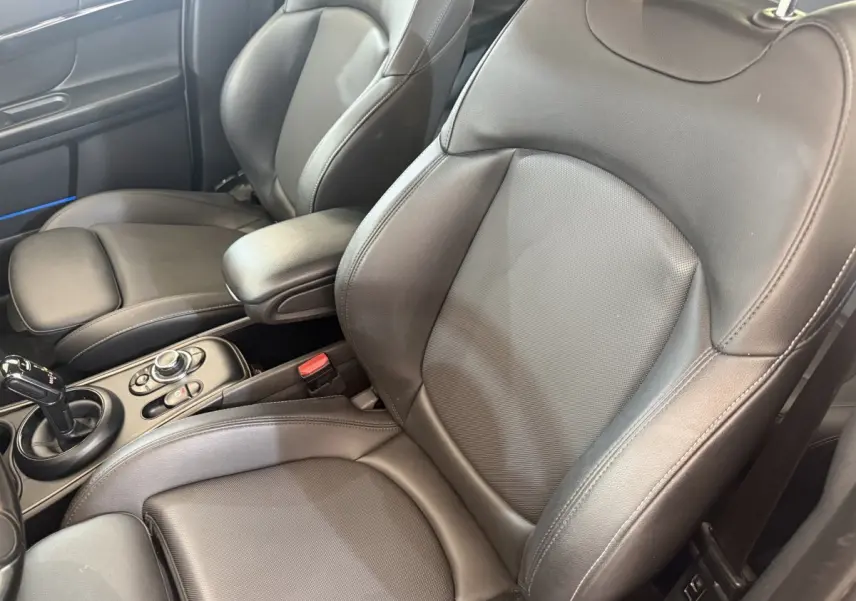 Gros plan sur les sièges avant en cuir noir et la console centrale d'une MINI Countryman gris clair, vue côté droit.
