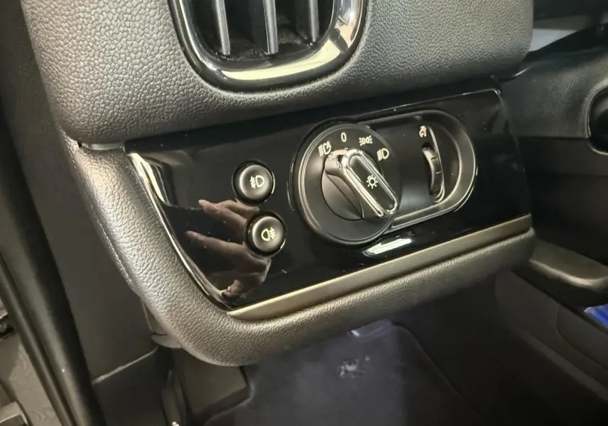 Gros plan sur le panneau de commande des phares et antibrouillards du tableau de bord noir du MINI Countryman gris clair.