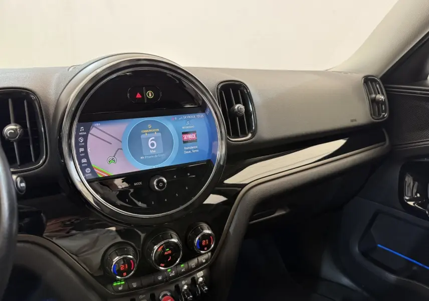 Vue intérieure côté passager du tableau de bord noir brillant du MINI Countryman 2023 avec écran tactile rond central.