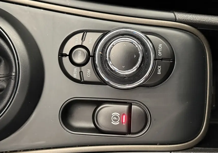 Vue rapprochée de la molette de commande multimédia et du frein à main électrique sur la console centrale d’une MINI Countryman gris clair.