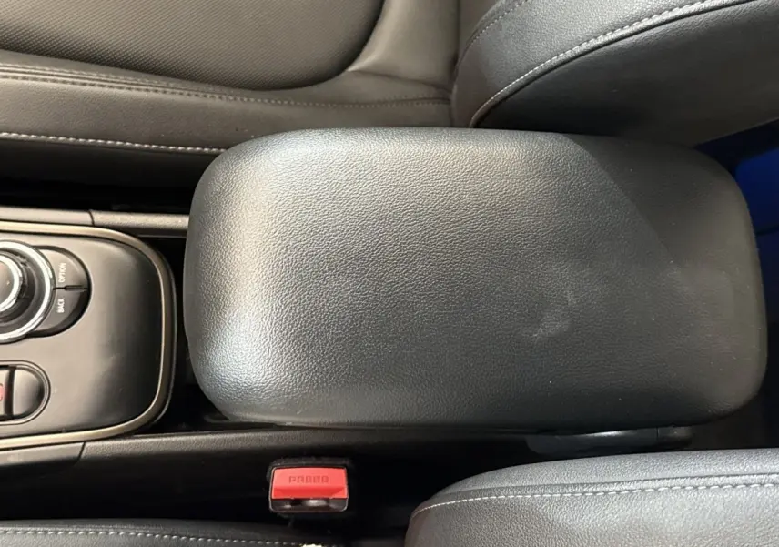 Vue rapprochée de l'accoudoir central en cuir noir et des commandes de la console centrale d'une MINI Countryman gris clair.