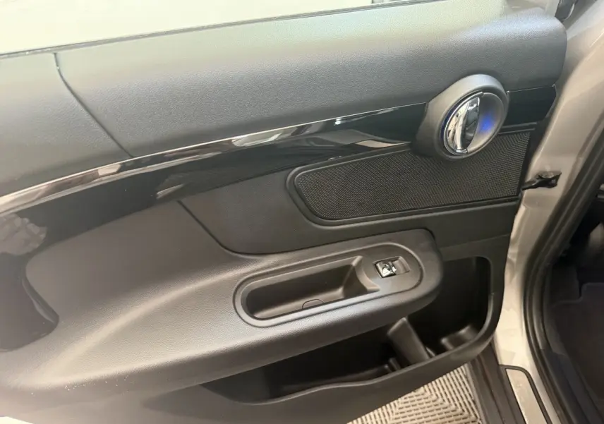 Vue rapprochée de la porte avant droite gris clair d’un MINI Countryman 2023 avec poignée chromée et commande de vitre.
