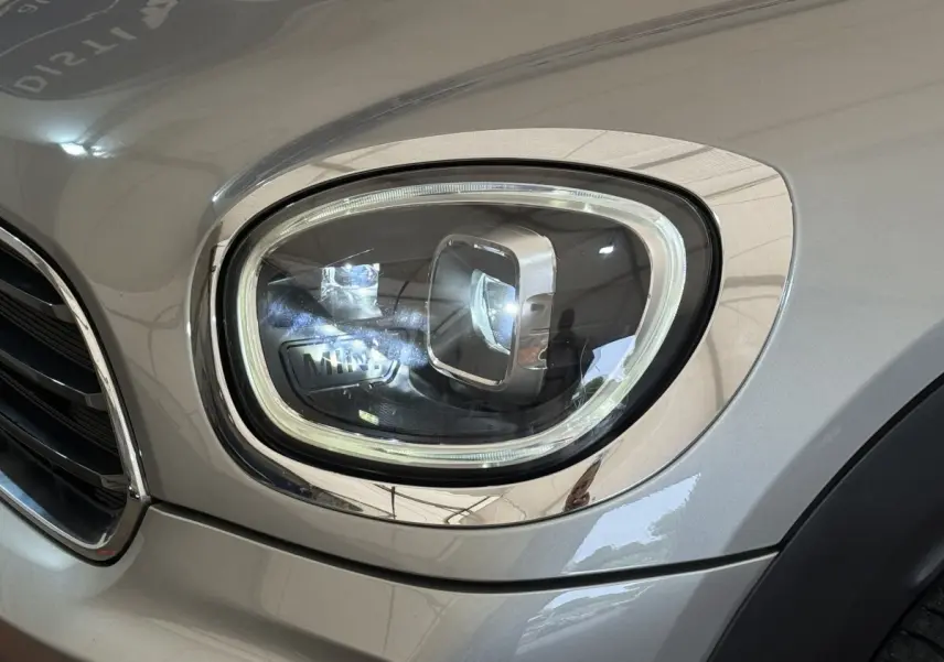 Gros plan sur le phare avant droit gris clair du MINI Countryman Cooper Essential 2023 avec détails chromés.