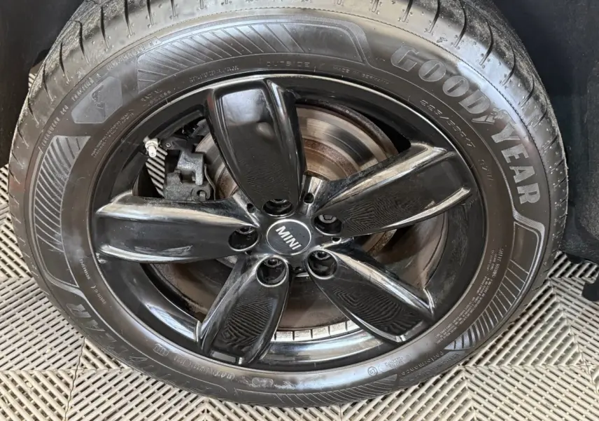 Gros plan sur la jante noire brillante à 5 branches du MINI Countryman gris clair, avec pneu Goodyear visible.