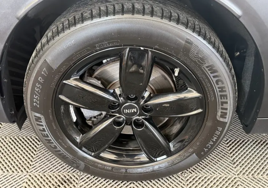 Gros plan sur la jante noire brillante et le pneu Michelin d'une MINI Countryman gris clair, côté roue avant.
