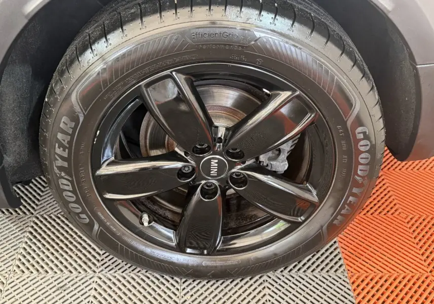 Gros plan sur la roue avant droite d’une MINI Countryman gris clair avec jante noire brillante et pneu Goodyear.