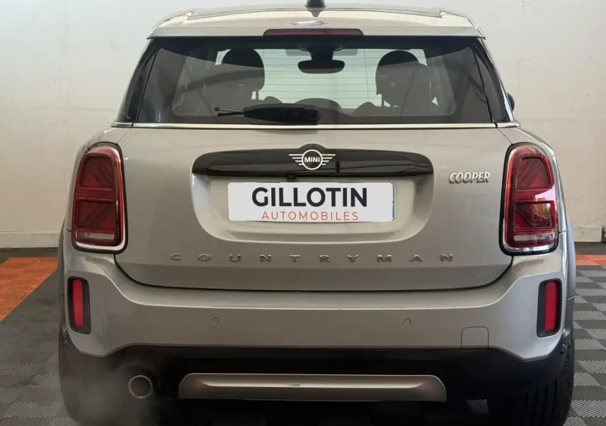 Vue arrière d'une MINI Countryman Cooper gris clair avec feux arrière rectangulaires et logo MINI centré.