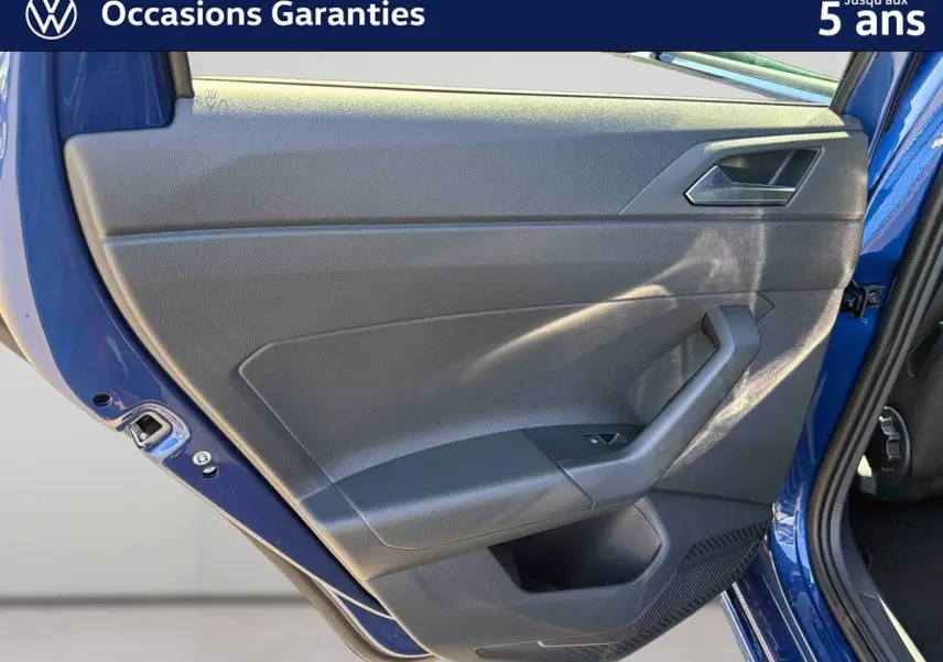 Vue intérieure sur la porte arrière droite bleu métallisé du Volkswagen Taigo avec panneau noir et poignée intégrée.