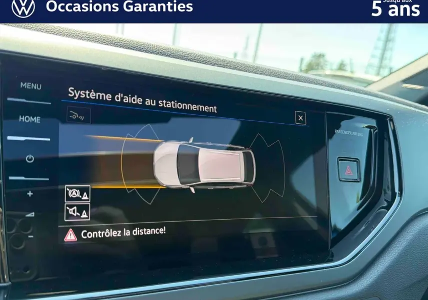 Écran tactile intérieur montrant l'aide au stationnement du Volkswagen Taigo bleu, vue de face côté conducteur.