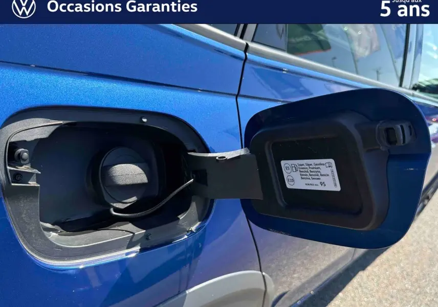 Détail de la trappe à carburant ouverte sur le côté gauche d’un Volkswagen Taigo bleu métallisé.