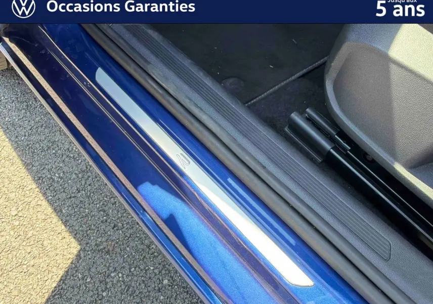 Gros plan sur la porte côté conducteur d'un Volkswagen Taigo bleu métallisé avec seuil de porte en aluminium.