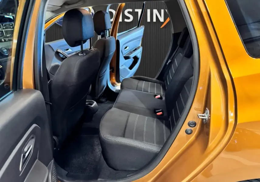 Vue intérieure côté droit arrière du Dacia Duster orange 2020, montrant les sièges arrière noirs et la porte ouverte.