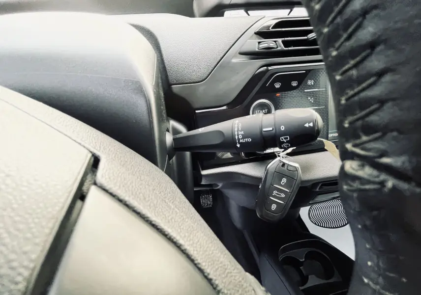 Gros plan sur la clé et le commodo d'essuie-glace côté gauche du tableau de bord gris d'une Citroën C4 Picasso II.