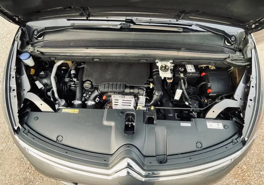 Vue plongeante sur le moteur essence gris d'une Citroën C4 Picasso II 2018 avec capot ouvert et logo chromé visible.