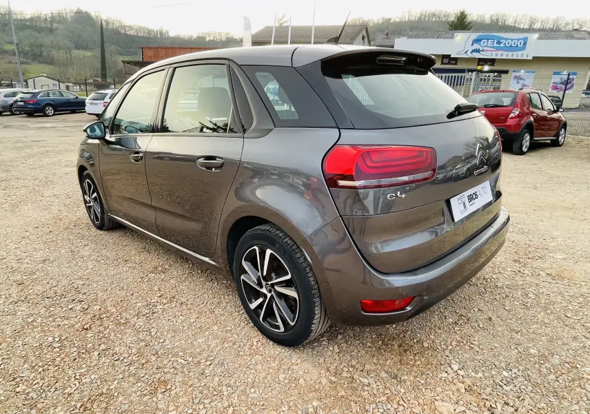 Vue 3/4 arrière droite d'une Citroën C4 Picasso gris métal avec feux arrière rouges et jantes alliage noires.