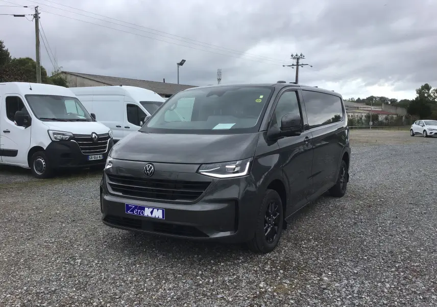 Vue 3/4 avant d'un Volkswagen Transporter T7 gris anthracite avec projecteurs LED Matrix et barres de toit repliables.