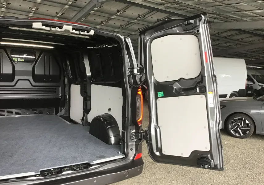 Vue arrière ouverte du Volkswagen Transporter T7 gris anthracite montrant l'espace de chargement intérieur et les portes battantes.