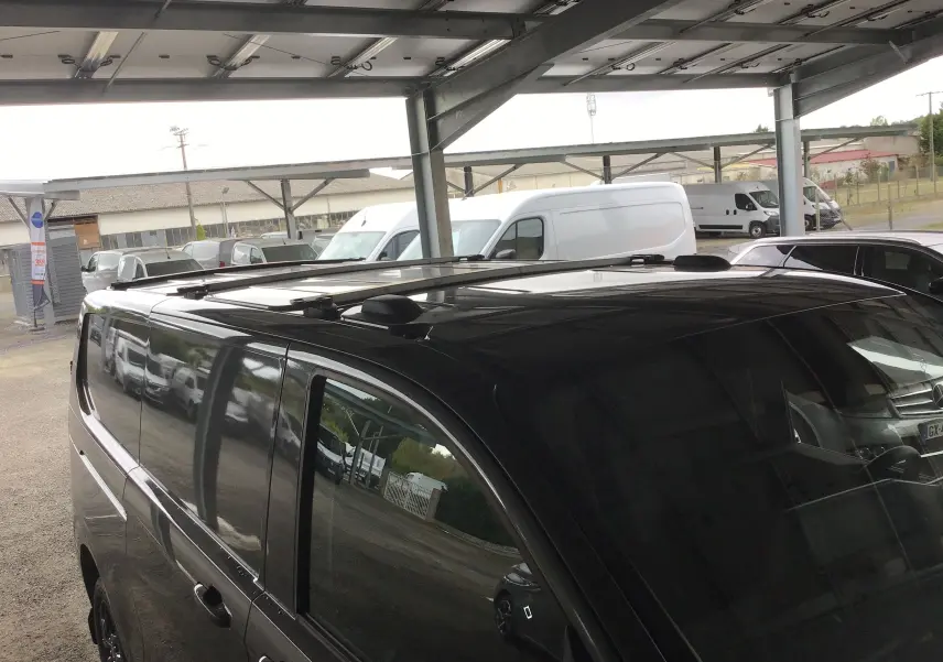 Vue de dessus et côté gauche d’un Volkswagen Transporter T7 gris anthracite avec barres de toit repliables sous abri.