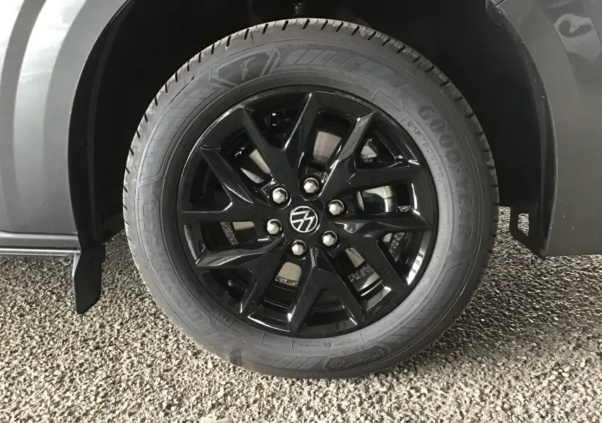 Gros plan sur la roue avant droite du Volkswagen Transporter gris anthracite avec jante noire brillante et pneu Goodyear.