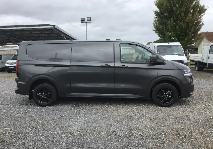 Profil latéral droit d'un Volkswagen Transporter T7 gris anthracite avec jantes noires et barres de toit repliables.