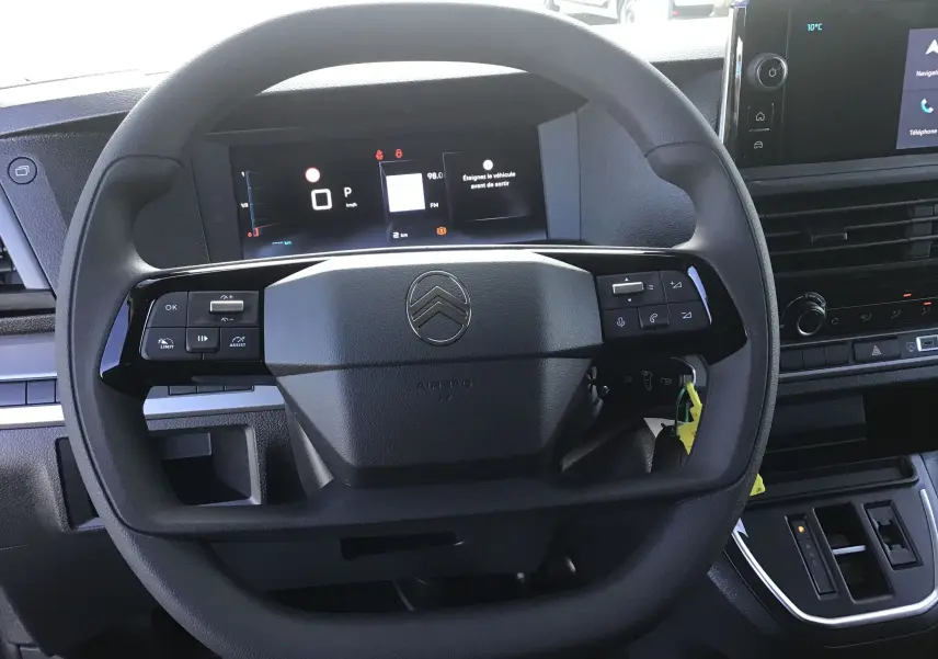 Vue rapprochée du volant noir du Citroën Jumpy XL gris titane, avec tableau de bord numérique et écran central visible.