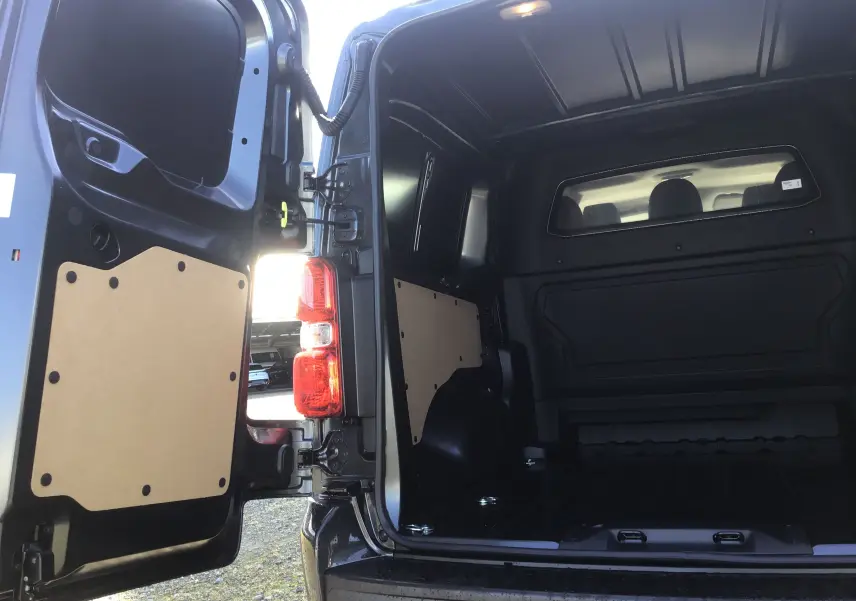 Vue arrière ouverte du Citroën Jumpy XL gris titane montrant l'espace de chargement vide et les portes arrière garnies.