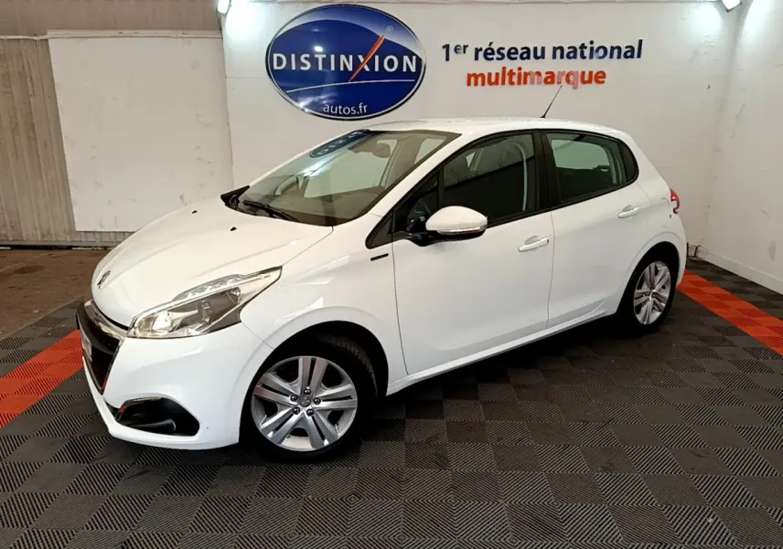 Peugeot 208 Puretech 82 Signature blanc vue 3/4 avant droit dans un showroom avec sol à damier noir et rouge.