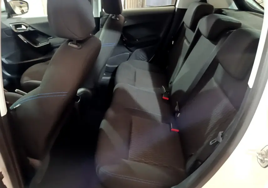 Vue intérieure côté droit montrant la banquette arrière noire avec surpiqûres bleues d'une Peugeot 208 blanche Puretech 82 Signature 2018.