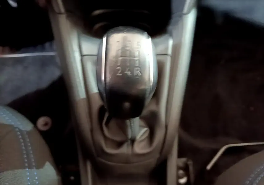 Le levier de vitesses manuel de la Peugeot 208 Puretech 82 Signature vu de dessus, intérieur sombre.